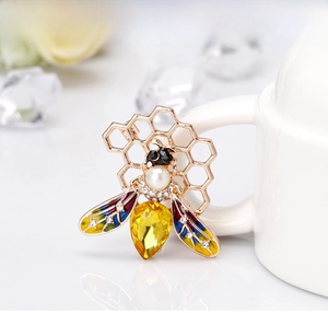 Macro shot of honeybee brooch featuring yellow gemstone, pearl head, and enamel wings