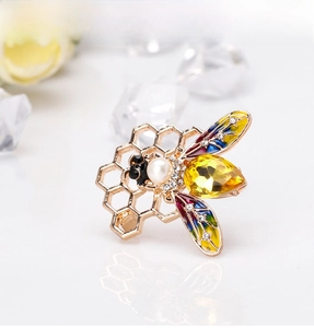 Detailed close-up of a bee brooch with yellow gemstone, enamel wings, and pearl accents