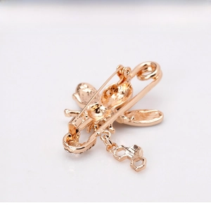 Detailed view of a golden bee brooch featuring a honeycomb pendant and safety pin back