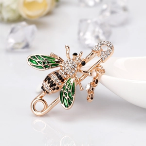 Elegant gold bee brooch pin with green enamel wings and crystal rhinestones on white