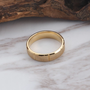 Gold stainless steel ring with brushed texture and polished edges on marble