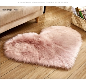 Close-up of a soft pink heart-shaped plush rug on a light wood floor in a cozy room