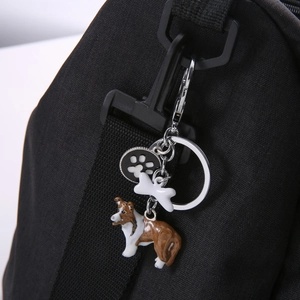 Detail of Corgi dog keychain with bone charm and paw print tag on black canvas bag
