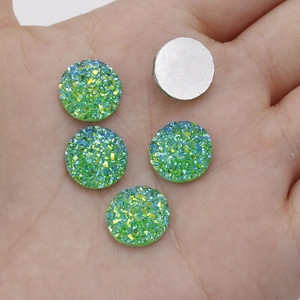 Detailed macro view of 12mm green resin cabochons with sparkling texture on palm