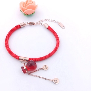 Detail of red braided lucky bracelet with rose gold coins and translucent gourd charm