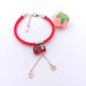 Close-up of red woven bracelet with gourd pendant and hollow copper coin charms