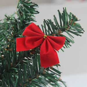 Set of 12 red flocked Christmas bows with gold ties hanging on a green pine tree branch