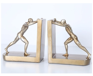 Detail of golden athletic male figurines used as creative bookends for shelf decor