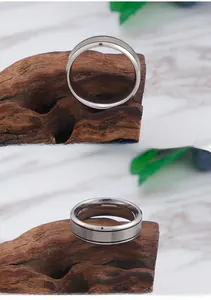 Detail of matte titanium steel ring with double black parallel lines on marble surface