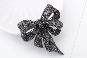 Detailed macro view of an ornate black metal bow brooch with intricate hollow-out design