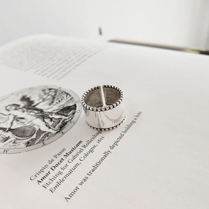 Macro shot of a wide 925 silver open ring with beaded edges on a vintage book