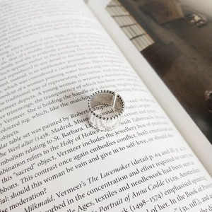Close-up of vintage 925 silver wide band ring with beaded edges on artistic book page