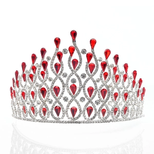 Detailed view of silver bridal crown with red teardrop rhinestones on white background