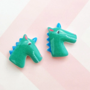 Detail of green and blue resin unicorn DIY accessories on a striped background