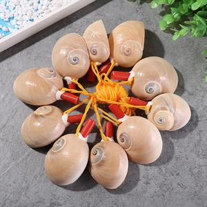 Close-up of natural conch shell whistle craft with orange braided rope and red cap