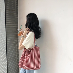 Detail of red and white gingham canvas tote bag with drawstring ties for daily use