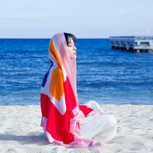 Outdoor shot of a colorful geometric patchwork beach shawl on a white sand beach