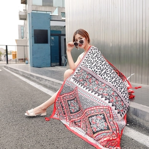 Detailed view of ethnic print shawl with vibrant floral patterns and red tassel accents