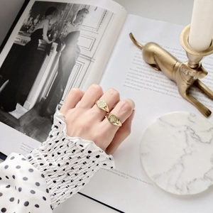 Detail of vintage gold engraved signet rings with sun and eye patterns on model hands