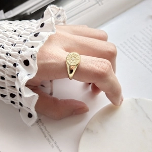 Close-up of gold starburst engraved ring with small diamond on a model hand