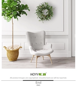 Detail of grey fabric armchair with wooden legs in a minimalist Nordic interior scene