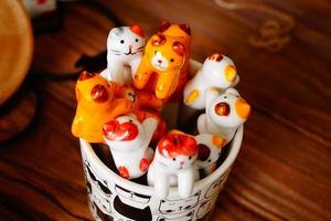 Detail of hand-painted ceramic cat stir spoons in a matching white and orange mug