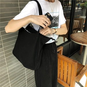 Detail of a large black canvas tote bag with white lettering and zipper closure
