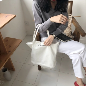Detail of white cotton canvas tote bag with black merciparis print on double handles