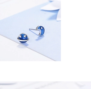 Macro shot of blue glitter planet and moon stud earrings with silver star details