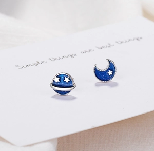 Detail of asymmetric blue glitter planet and moon stud earrings with silver accents