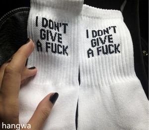Detail shot of white cotton socks featuring black I DON'T GIVE A FUCK slogan print