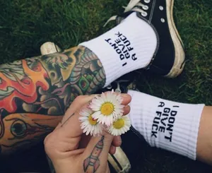 White cotton crew socks with black bold text on green grass background