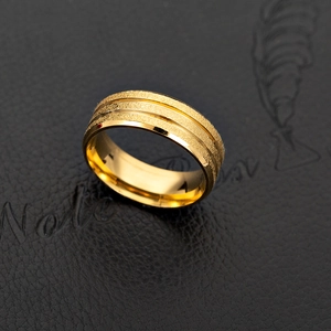 Macro shot of gold wide band ring with frosted finish and parallel polished lines