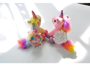Close-up of pink and yellow plush unicorn keychains with sequins and gold metal hooks