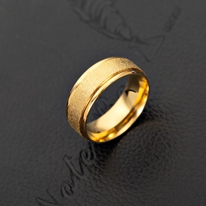 Macro detail of gold-plated stainless steel ring with brushed texture and mirror edges