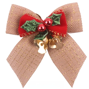 Close-up of burlap Christmas bow with gold thread, holly leaves and small golden bells
