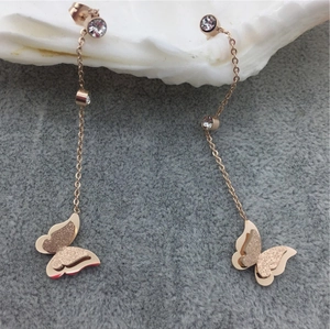18K rose gold butterfly earrings with crystal accents on a soft grey velvet display