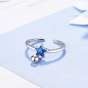 Minimalist silver open ring with blue star charm and small bead pendant on floral background