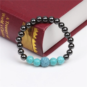 Detail of beaded magnetic bracelet with turquoise and volcanic stone on vintage book