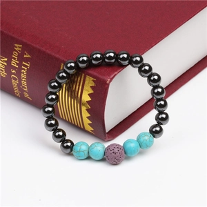 Close-up of magnetic beads and turquoise bracelet displayed on a red book cover