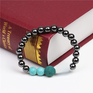 Detail of magnetic hematite and turquoise beaded bracelet resting on a red classic book