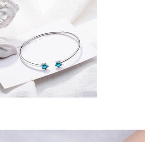 Detail shot of silver star bangle with blue crystals and minimalist design