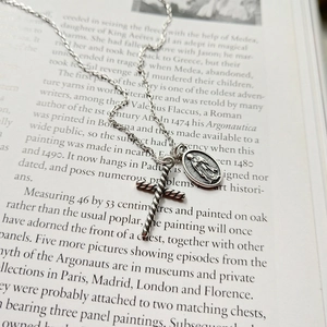 Detail of S925 sterling silver cross and Virgin Mary medal pendant on vintage book pages