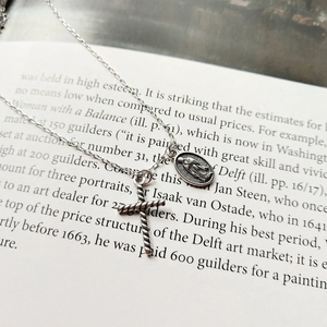 Macro detail of vintage 925 sterling silver cross and Virgin Mary pendants on an antique book