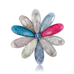 Macro shot of multicolored flower brooch with water drop petals and blue rhinestone center