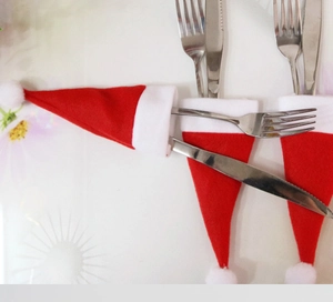 Red and white Christmas mini hat cutlery holders set on a white floral table