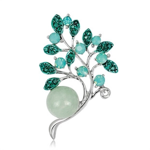Macro detail of silver Christmas tree brooch with green crystals and a large pale pearl