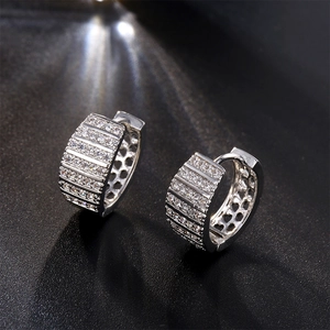 Elegant silver hoop earrings featuring rows of sparkling zircons on a dark background