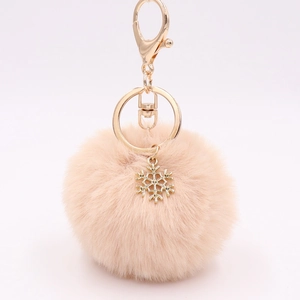 Detailed view of light pink fluffy pompom keychain with golden snowflake pendant and clasp