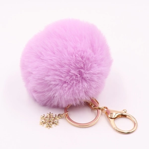 Detail of purple faux fur pompom keychain with golden snowflake charm and metal clasp